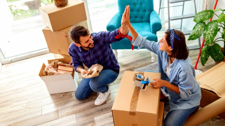 A young couple high fives one another as they enjoy decluttering before moving.
